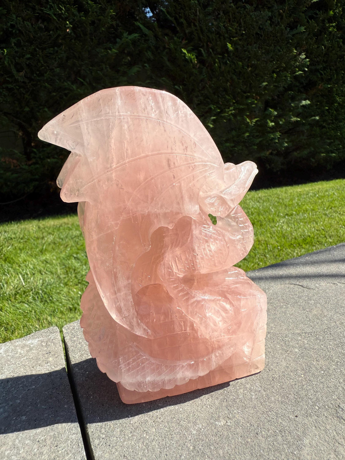 Close-up of rose quartz dragon carving showing intricate facial details and soft pink translucence.