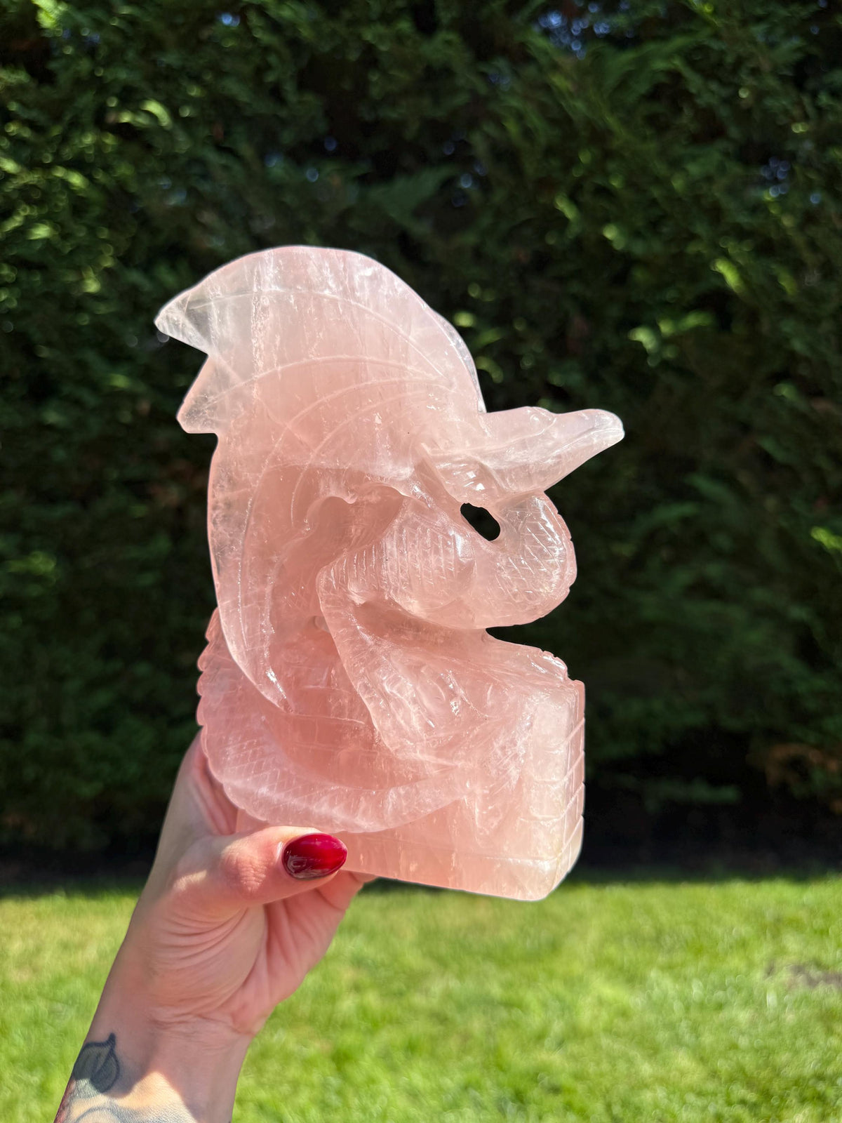 Large rose quartz dragon carving with detailed scales and a polished pink crystal body.