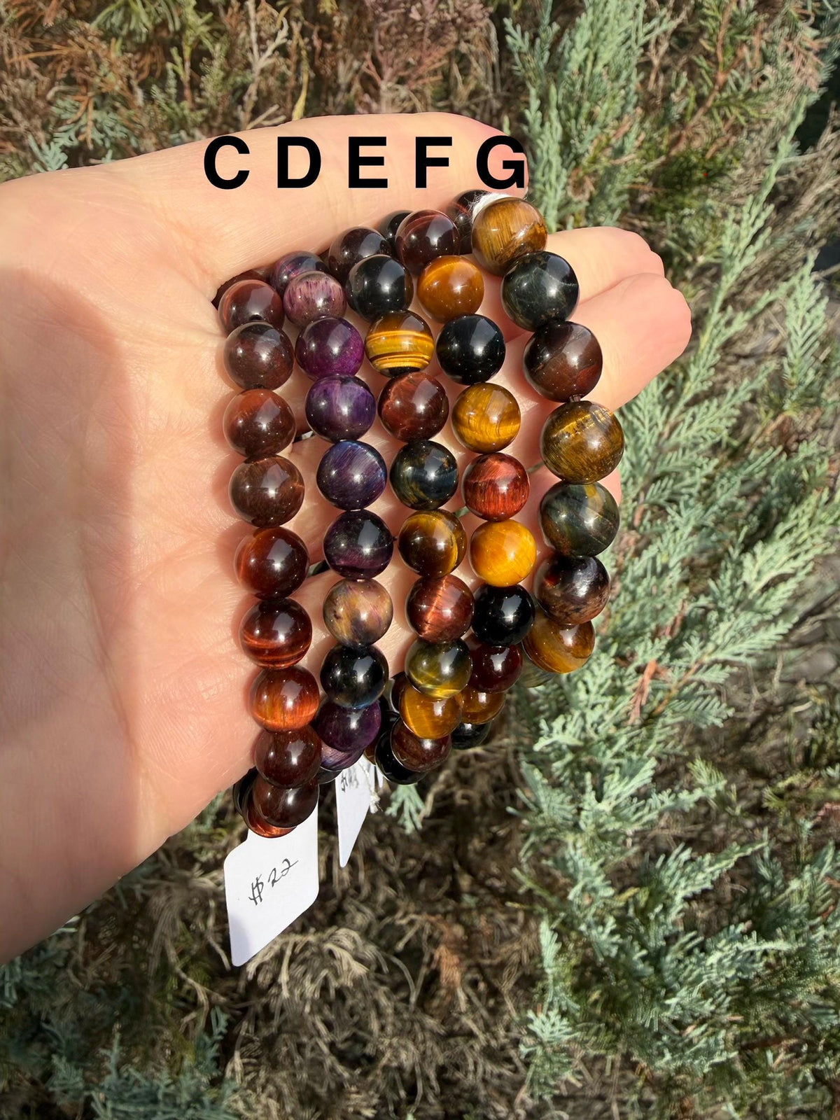 Close-up of multiple Tiger’s Eye bracelets showing gold, red, and blue banding.