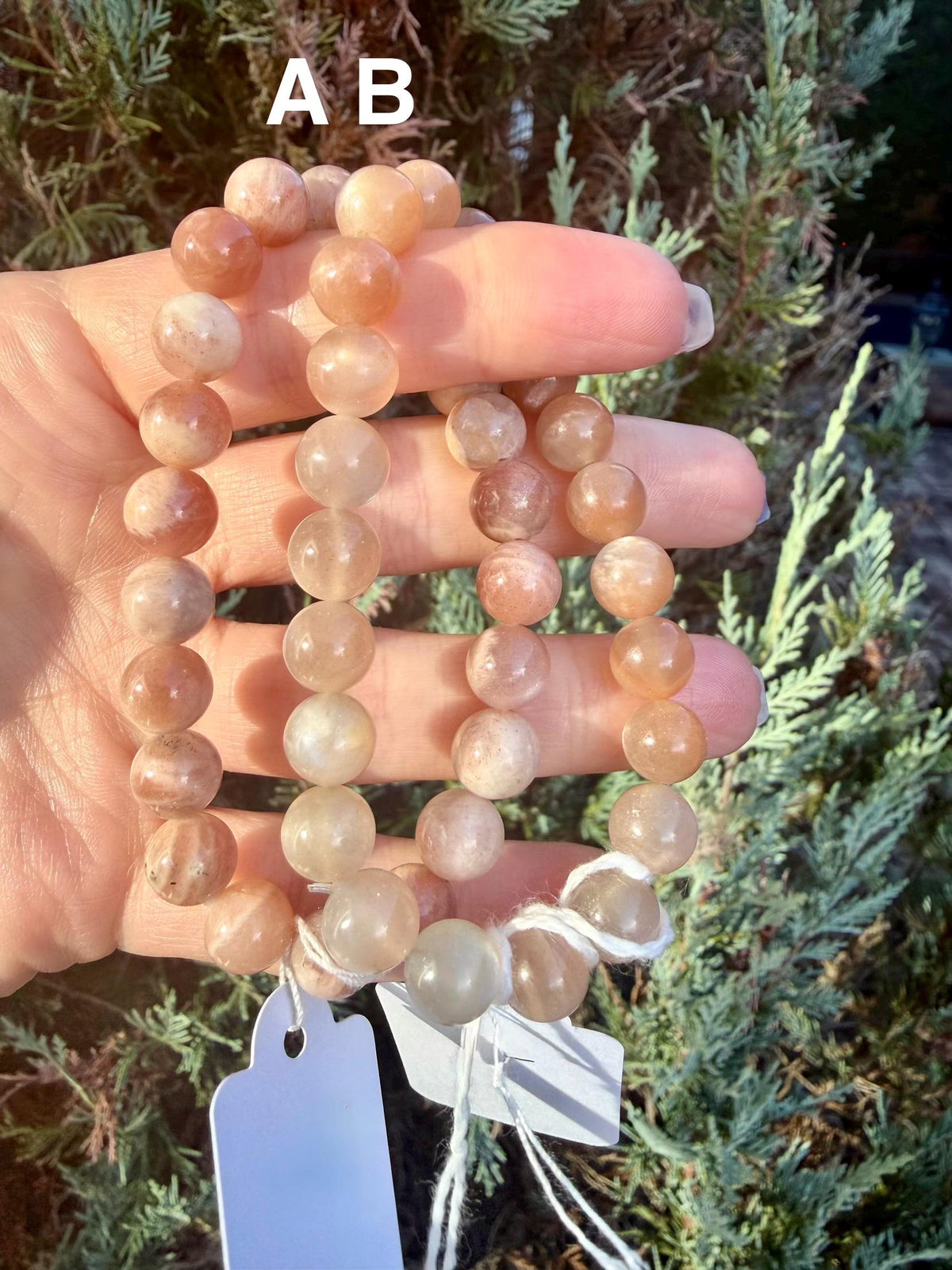 Stack of Peach Moonstone and Sunstone crystal bracelets with varying bead sizes, polished natural gemstones, and warm shimmer.