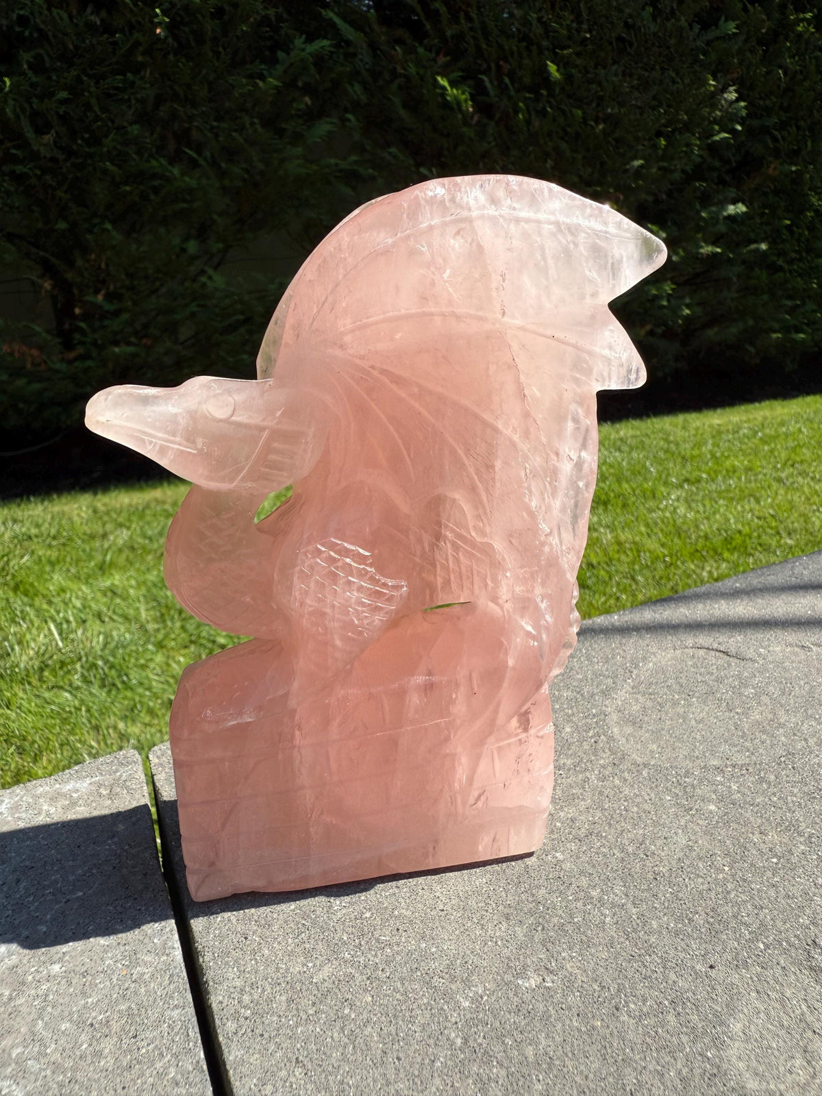 Side view of rose quartz dragon statue with carved scales and smooth polished finish.