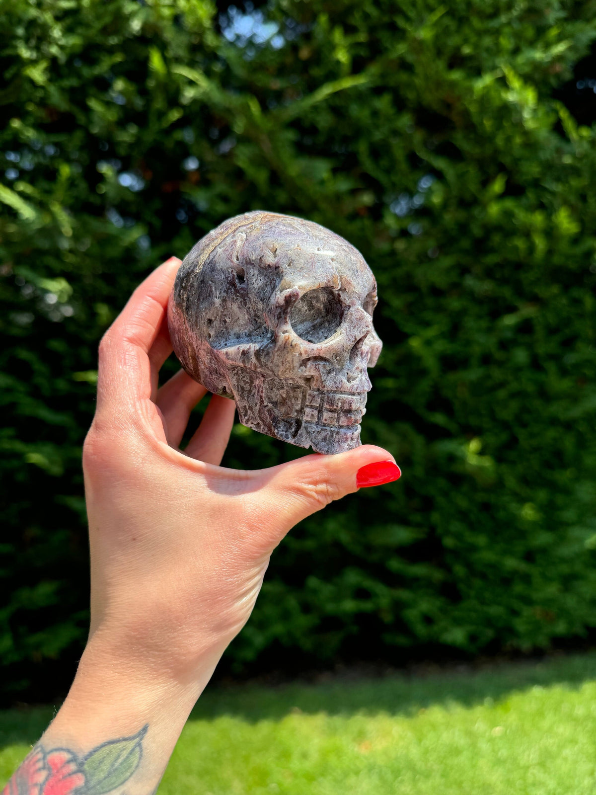 May include: A purple and grey crystal skull carved in the shape of a human skull.