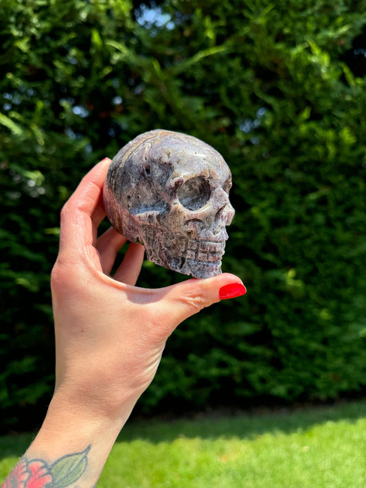 May include: A purple and grey crystal skull carved in the shape of a human skull.