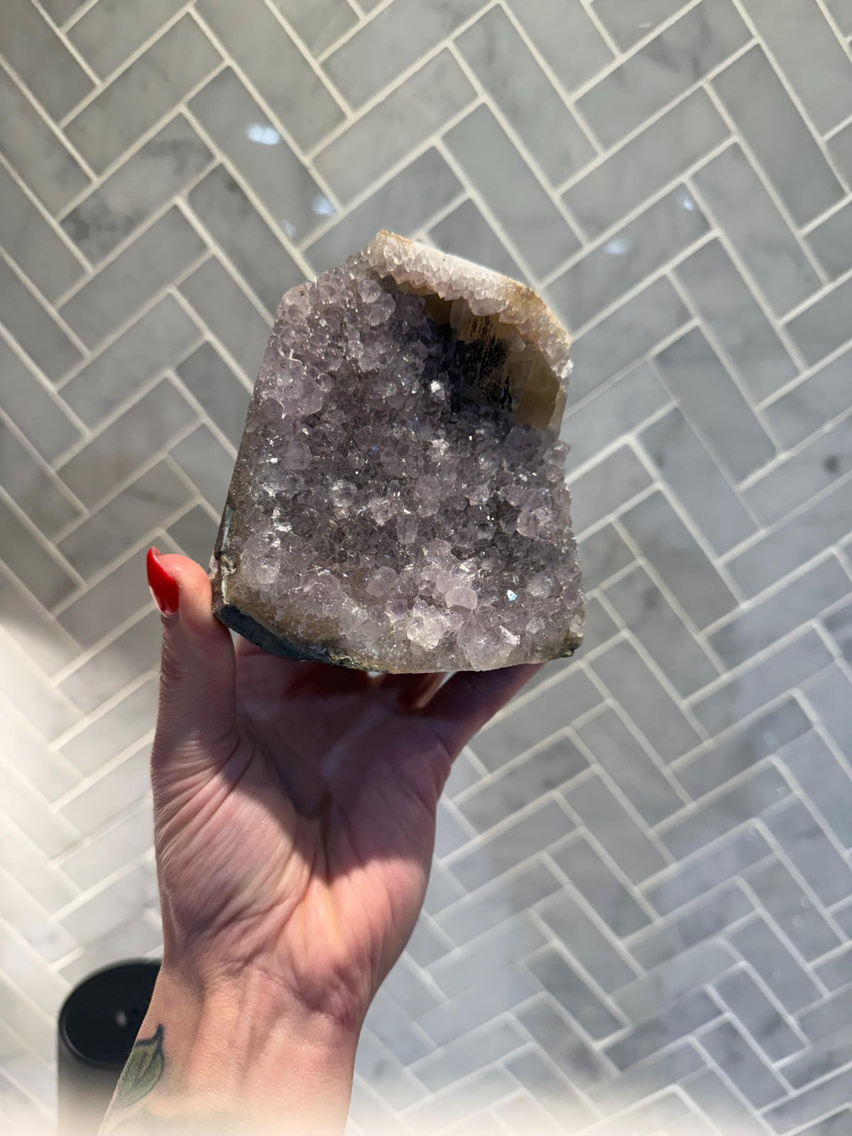 May include: A large amethyst crystal cluster with a natural, rough exterior and a smooth, polished interior. The crystal is a deep purple color and has a variety of sizes and shapes of crystals.